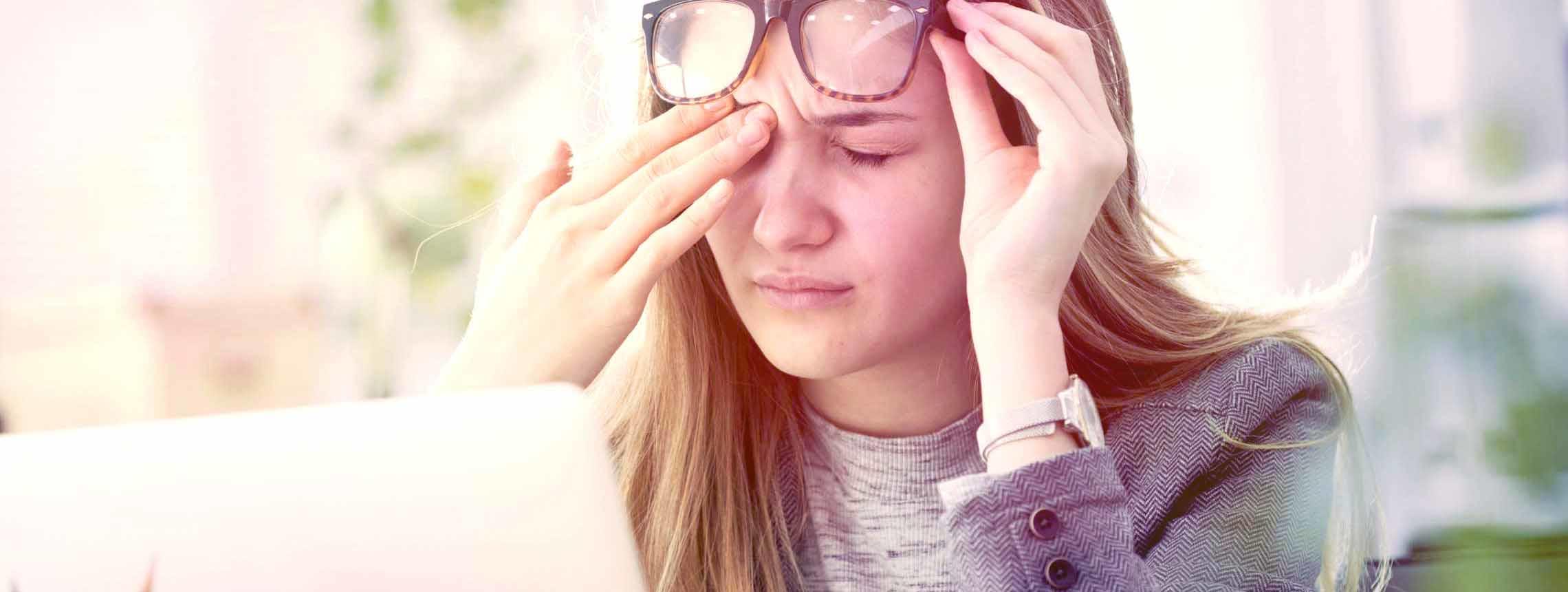 MS und ich: Symptome, Fatique – eine Frau vorm Notebook schiebt ihre Brille hoch und reibt ihr rechte Augenlid