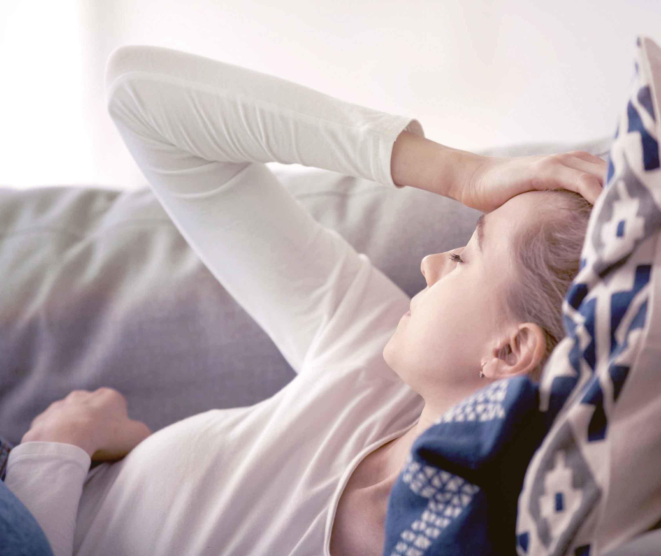 MS und ich: Eine Frau liegt auf dem Sofa und hält sich eine Hand an die Stirn