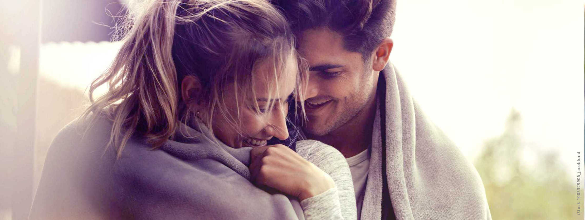 MS und ich: Ein Mann nimmt seine Partnerin liebevoll in den Arm. Bei sind in eine Decke gehüllt