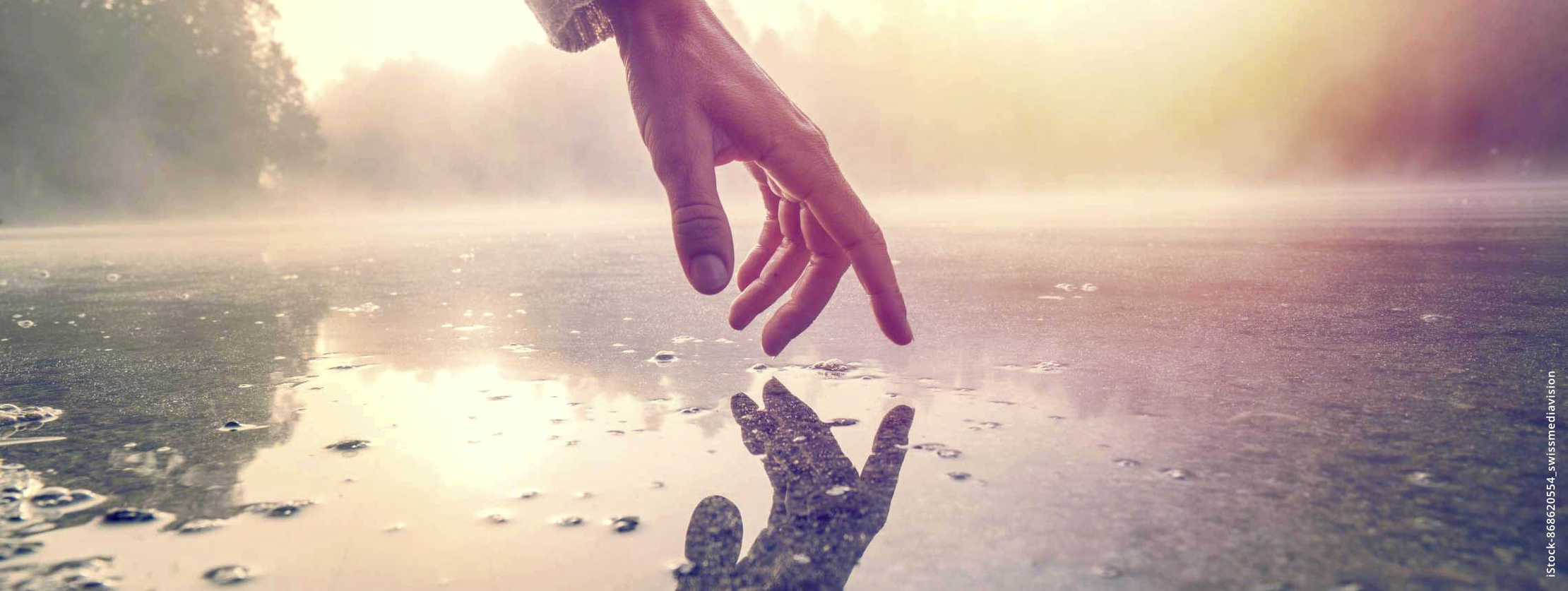 MS und ich: Eine ausgestreckte Hand berührt fast eine dunstige Wasseroberfläche