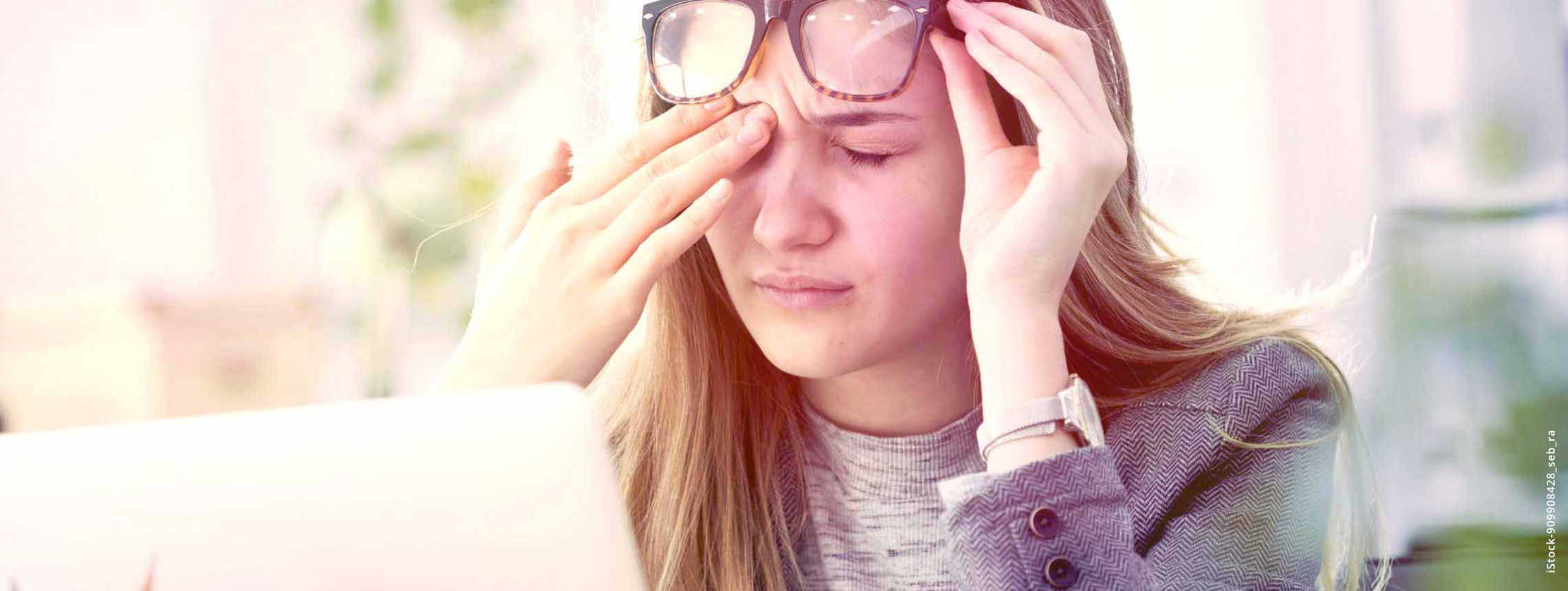 MS und ich: Symptome, Fatique – eine Frau vorm Notebook schiebt ihre Brille hoch und reibt ihr rechte Augenlid