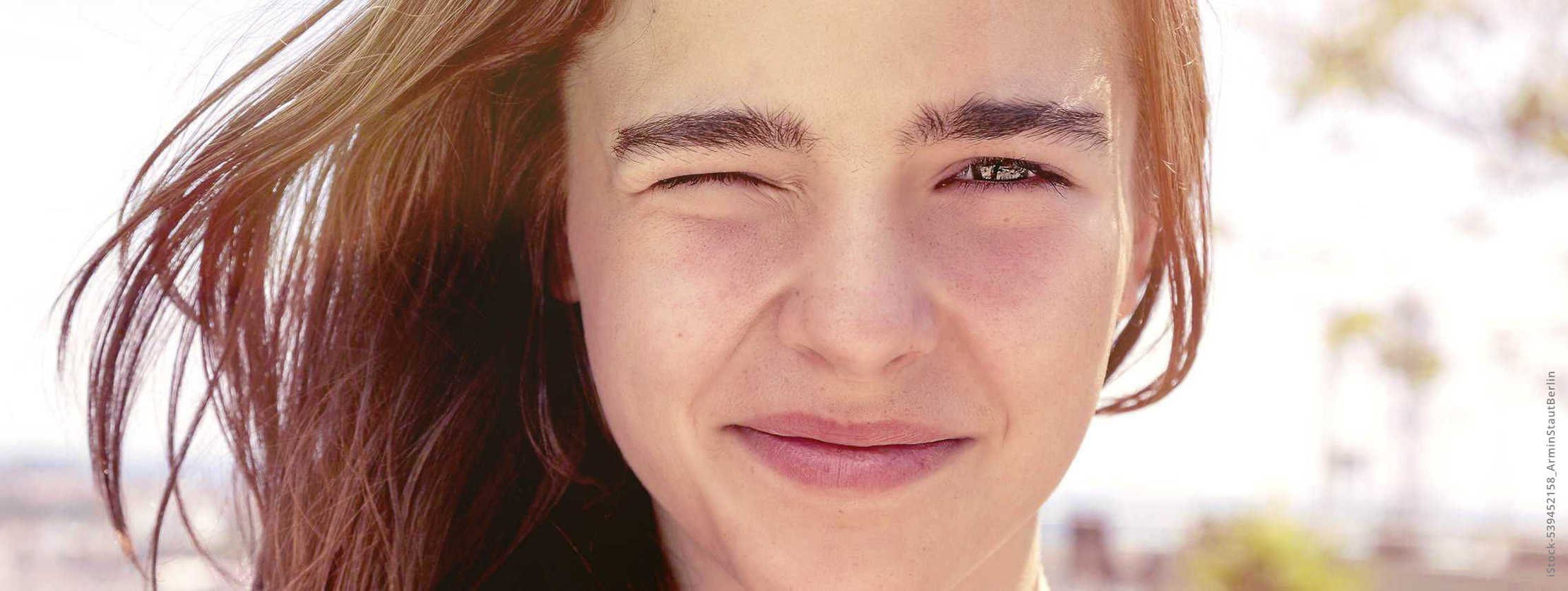 MS & ich: Eine junge Frau kneift ihr rechtes Auge zu