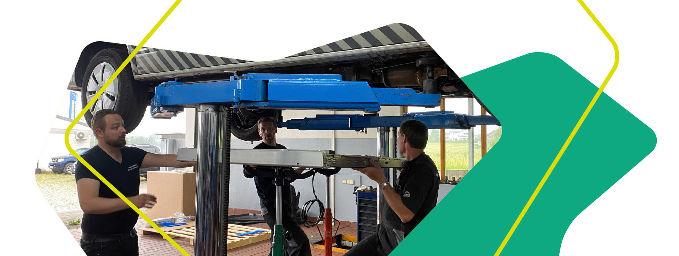 Auf dem Bild ist das Fahrzeug auf einer Hebebühne zu sehen und darunter arbeiten drei Männer an dem Fahrzeug.