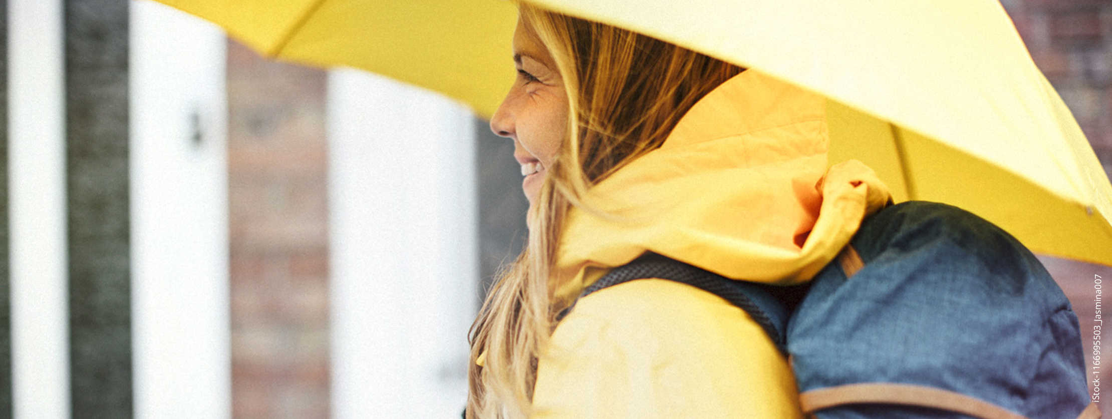 Eine Frau mit gelber Regenjacke und einem gelben Regenschirm.