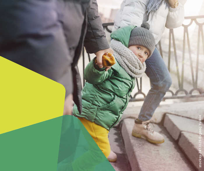 Ein Kleinkind an den Händen seiner Eltern