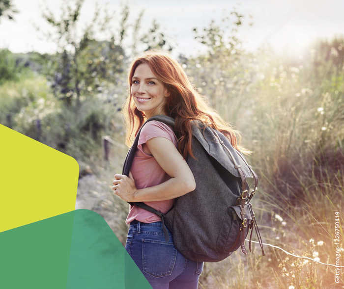 Junge Frau mit Rucksack dreht sich zur Kamera und lächelt