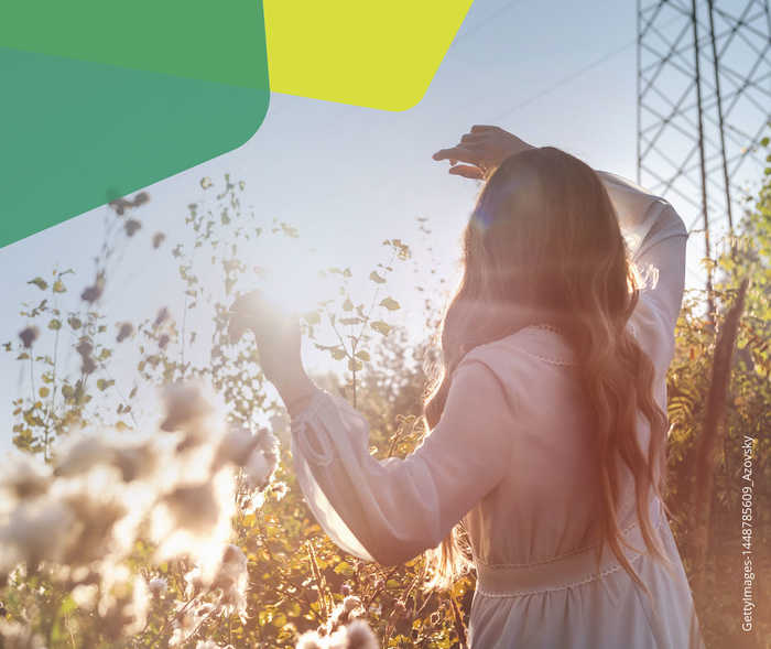Eine Frau im weißen Kleid, die der Sonne entgegen schaut.