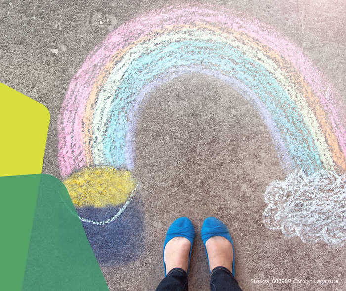 Ein aus Kreide gemalter Regenbogen auf Asphalt.