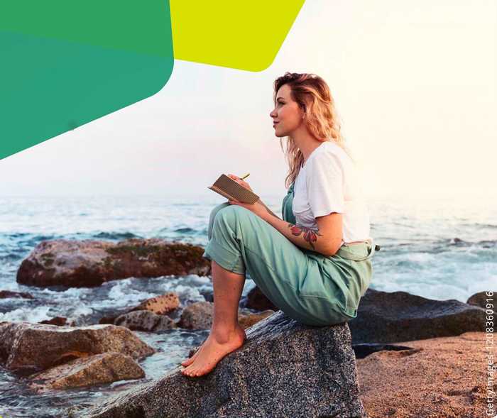 Das Bild zeigt eine Frau auf einem Felsen am Strand