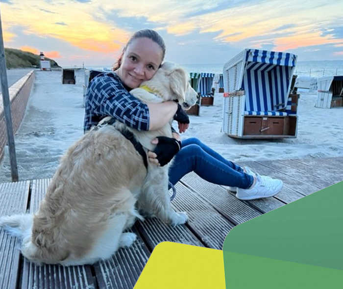 Solly und ihr Hund am Strand, im Hintergrund sind Starndkörbe.