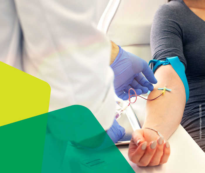 Bild von einer Blutabnahme bei einer Person in einem grauen Langarmshirt, welches zum Ellenbogen hochgekrempelt ist.