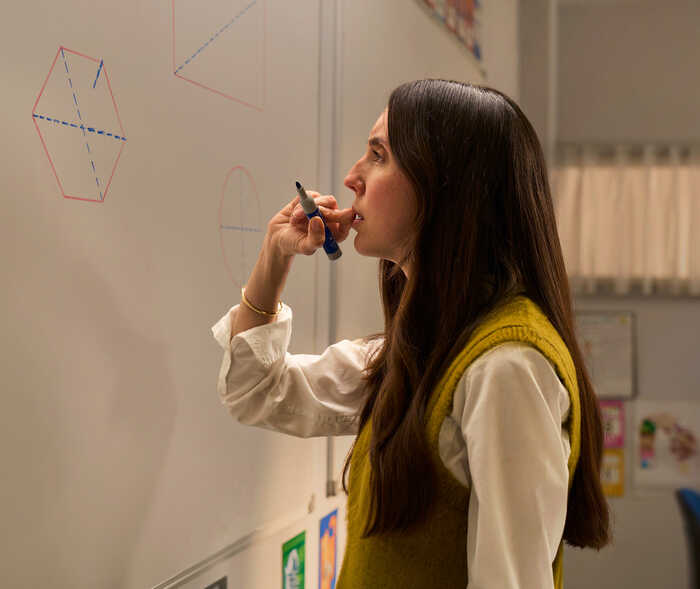Eine Frau steht mit einem Stift vor einem Whiteboard mit Zeichnungen.