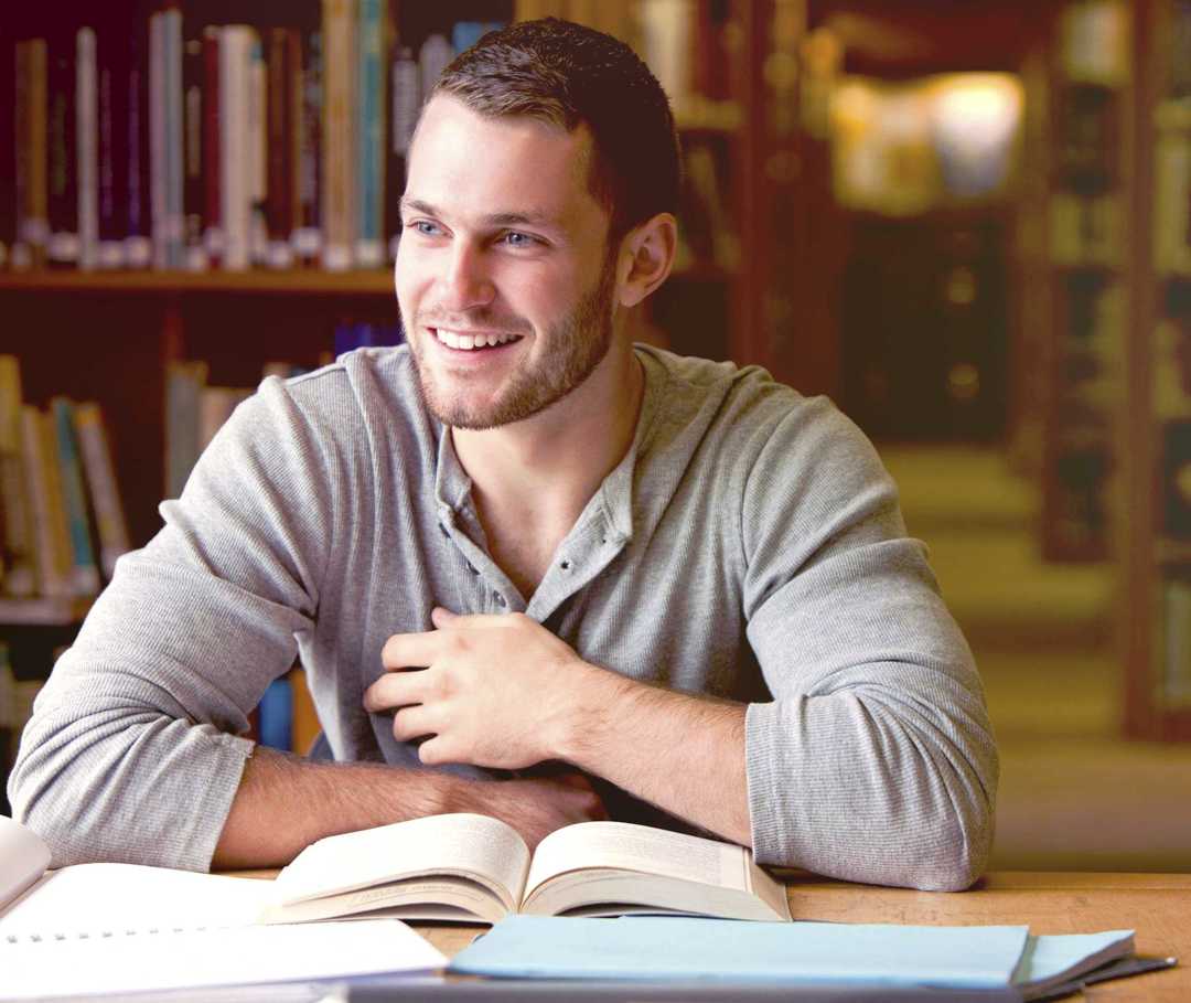 MS und ich: Ein junger mann blickt von seinen Büchern hoch und lächelt