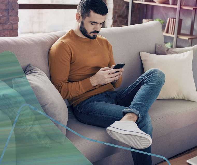 Mann auf Sofa schaut auf sein Smartphone