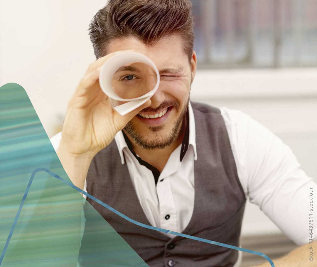 Mann schaut durch eine Papierrolle