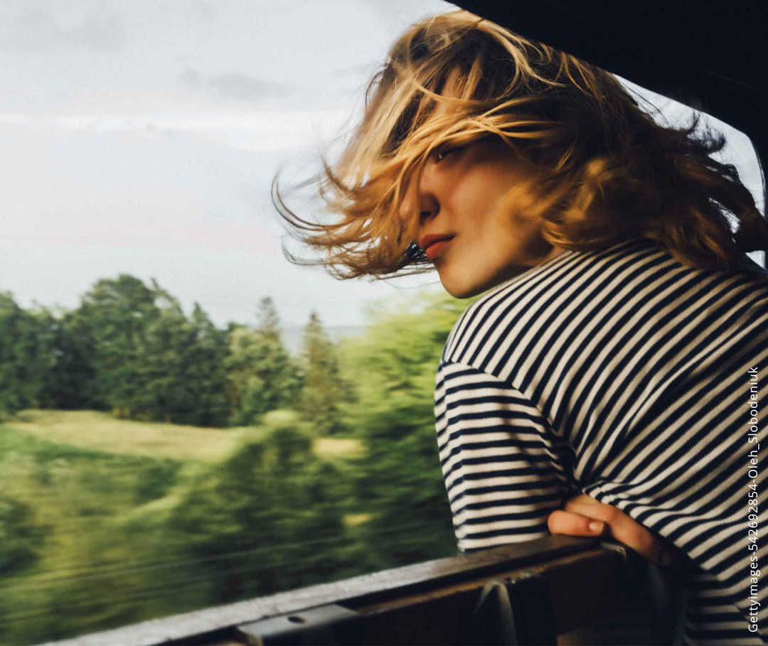 Multiple Sklerose: Eine Frau lehnt sich leicht aus dem Fenster eines fahrenden Zuges