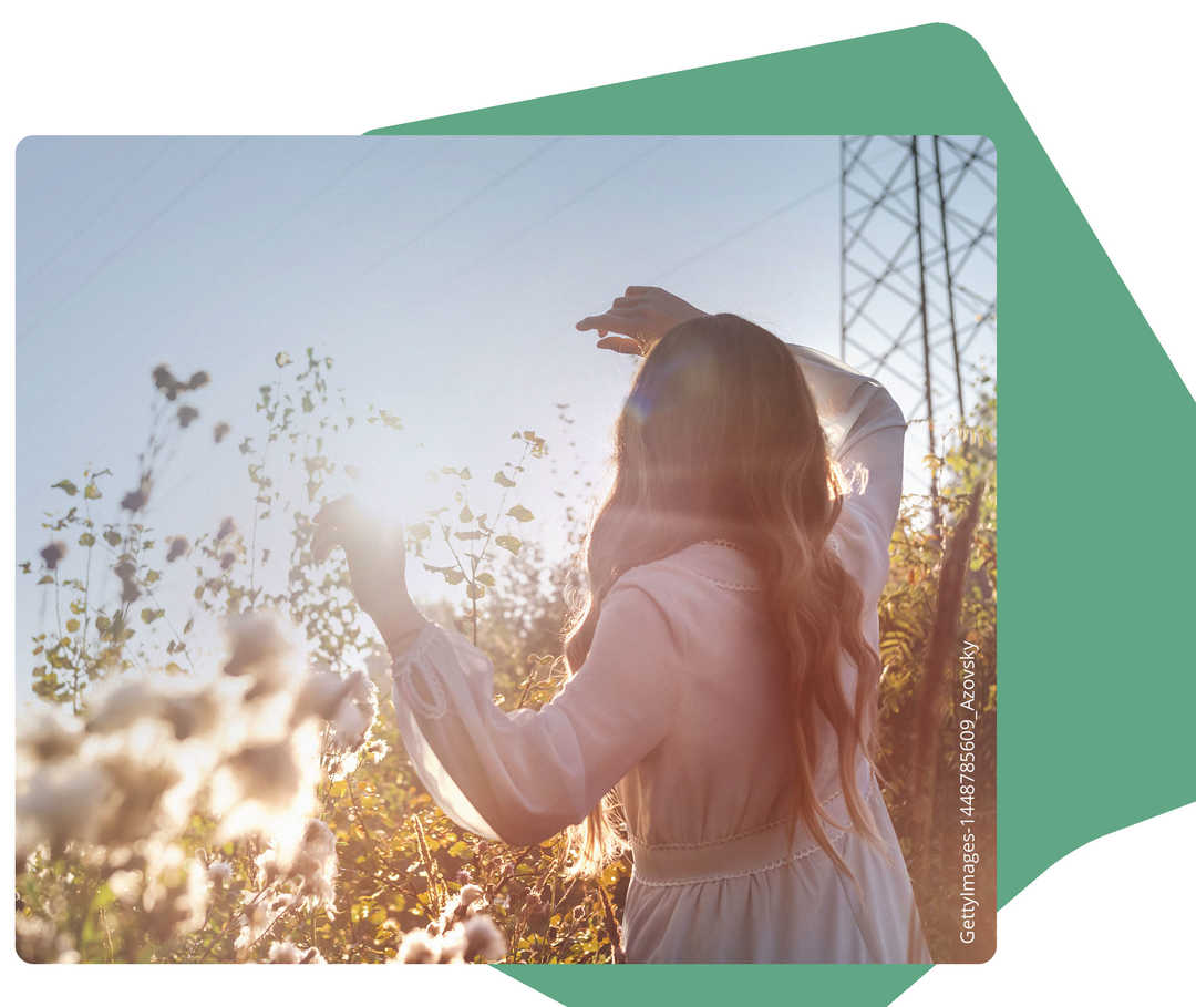 Eine Frau im weißen Kleid, die der Sonne entgegen schaut.