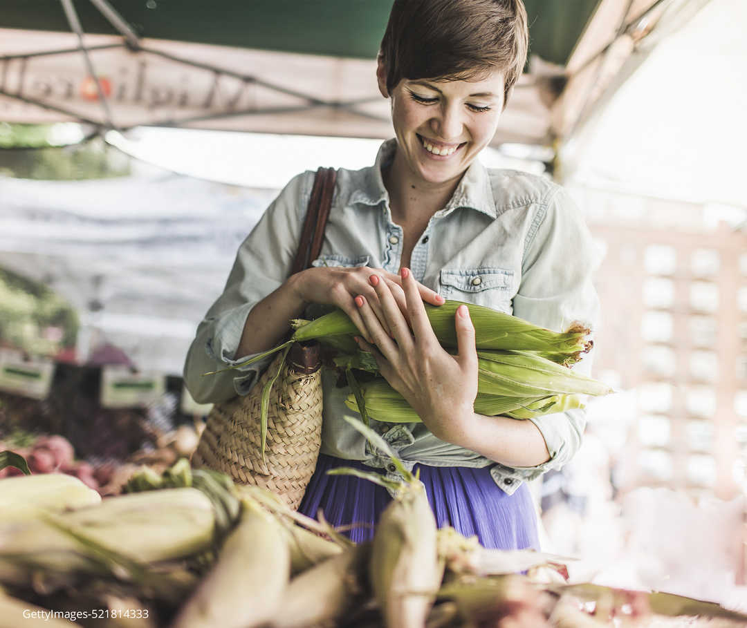 Eine Frau auf dem Markt mit Maiskolben in den Händen