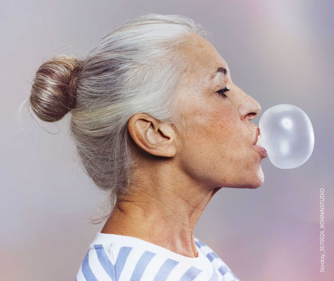 MS & ich Hormone Frau aus der Seitenansicht, die eine Kaugummi-Blase macht.